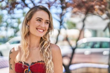 Young blonde woman smiling confident looking to the side at park