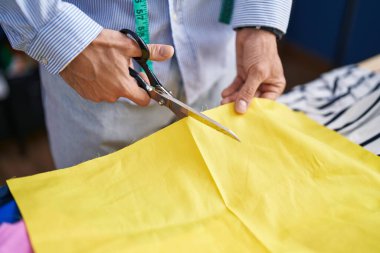 Genç İspanyol terzi dikiş atölyesinde kumaş kesiyor.