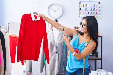 Young beautiful latin woman tailor make photo by smartphone to t shirt at florist