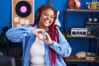 African american woman artist doing heart gesture with hands at music studio