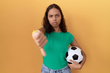 Genç İspanyol kadın topu tutarken mutsuz ve kızgın görünüyor. Reddedilmiş ve olumsuz bir hareket yapıyor. kötü ifade. 
