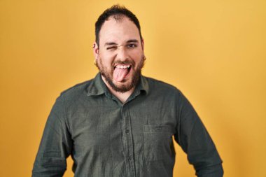 Ayrıca sarı arka planda dikilen sakallı, komik bir ifadeyle dilini dışarı çıkaran İspanyol bir adam. duygu kavramı. 