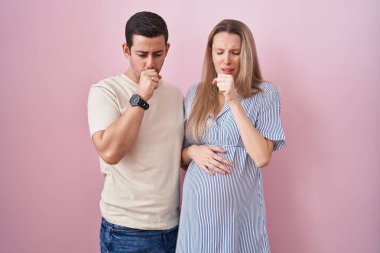 Pembe arka planda bebek bekleyen genç bir çift kendini iyi hissetmiyor ve soğuk algınlığı veya bronşitin belirtisi olarak öksürüyor. sağlık hizmeti kavramı. 