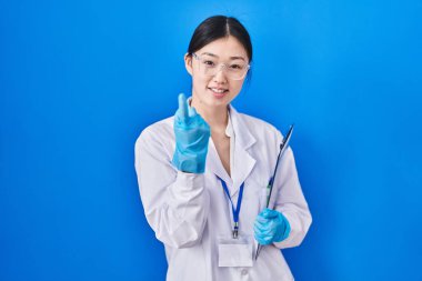 Laboratuvarda çalışan Çinli genç bir kadın buraya el kol hareketi yaparak mutlu ve gülümseyen insanları davet ediyor. 