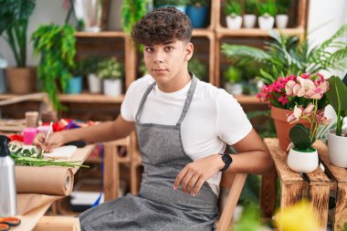 Çiçekçide deftere yazı yazan genç İspanyol çiçekçi.