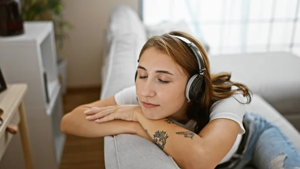 Evde Kanepede Müzik Dinleyen Genç Bir Kadın — Stok fotoğraf