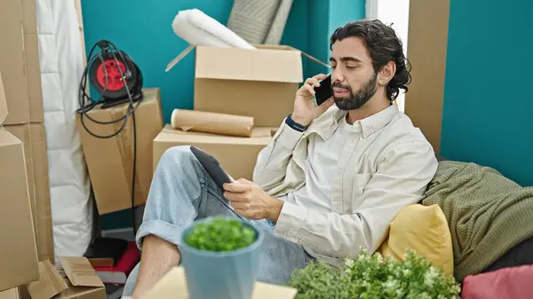 Young Hispanic Man Talking Smartphone Using Touchpad New Home — Stock Photo, Image