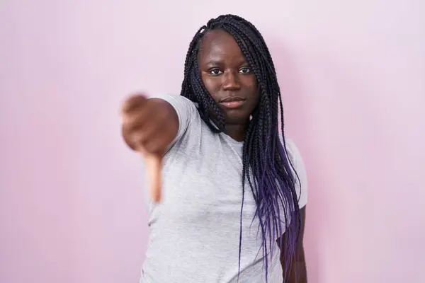 ピンクの背景の上に立っている若いアフリカの女性は 不幸で怒って 親指のジェスチャーで拒絶とネガティブを示しています 悪くない表現 — ストック写真