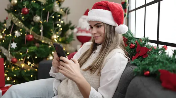 Νέα Όμορφη Ισπανόφωνη Γυναίκα Χρησιμοποιώντας Smartphone Κάθεται Από Χριστουγεννιάτικο Δέντρο — Φωτογραφία Αρχείου