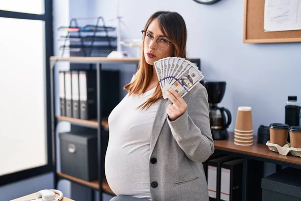 Těhotná Žena Drží Dolary Kanceláři Myšlení Postoj Střízlivý Výraz Hledá — Stock fotografie
