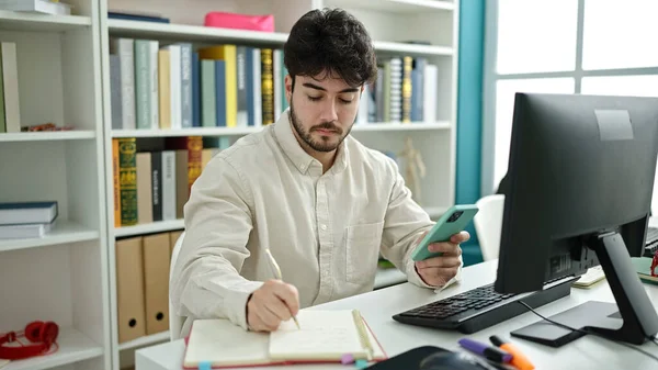 Jovem Estudante Hispânico Usando Computador Smartphone Escrevendo Notas Universidade Biblioteca — Fotografia de Stock
