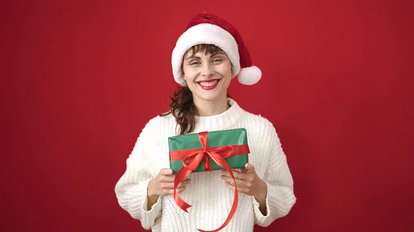 Νεαρή Καυκάσια Γυναίκα Χαμογελά Φορώντας Χριστουγεννιάτικο Καπέλο Κρατώντας Δώρο Πάνω — Φωτογραφία Αρχείου