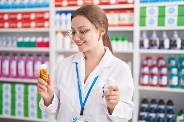 Mulher Loira Jovem Farmacêutico Sorrindo Confiante Segurando Duas Garrafas Pílulas — Fotografia de Stock