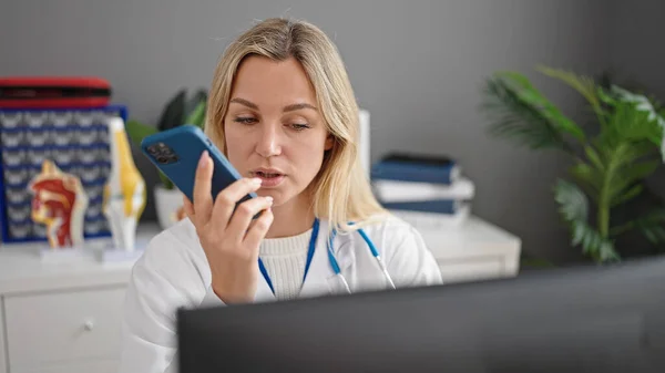 금발의 병원에서 스마트폰으로 메시지를 보내는 컴퓨터를 사용하는 — 스톡 사진