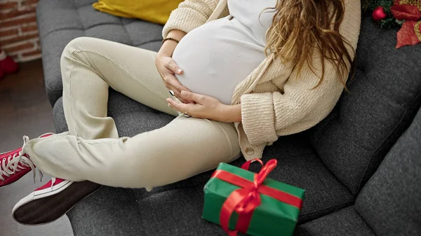 Mladá Těhotná Žena Dotýká Břicho Sedí Pohovce Vánočním Dárkem Doma — Stock fotografie