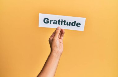 Hand of caucasian man holding paper with gratitude word over isolated white background