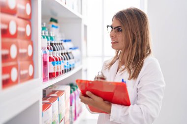 Young woman pharmacist writing on document at pharmacy