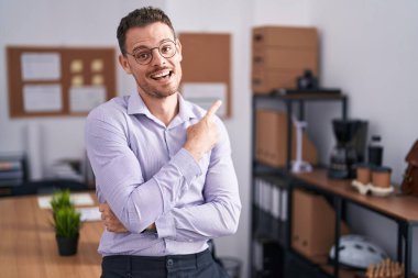 Ofisteki genç İspanyol adam yüzünde kocaman bir gülümsemeyle, kameraya el ile işaret ederek bakıyor.. 