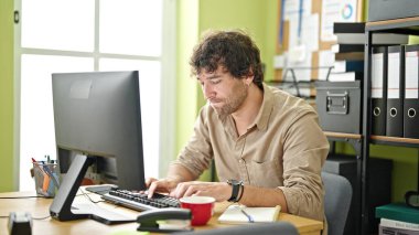 Ofisteki bilgisayarı kullanan İspanyol bir iş adamı.