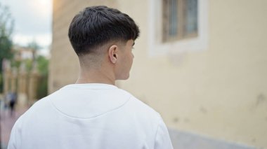 Genç İspanyol adam caddede geri geri duruyor.