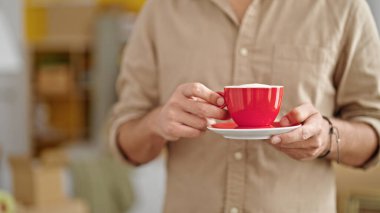 Genç İspanyol adam yeni evinde elinde bir fincan kahve tutuyor.