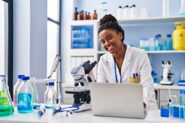 African american woman scientist using laptop working at laboratory