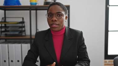 African american woman business worker sitting on table speaking at office