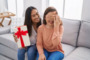 İki kadın anne ve kız evde hediyeyle sürpriz yapıyorlar.