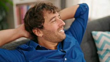 Genç İspanyol adam, ellerini başının üstüne koyup evinde kanepede oturarak rahatladı.