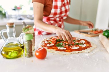 Genç, güzel İspanyol kadın mutfakta İtalyan pizzası hazırlıyor.