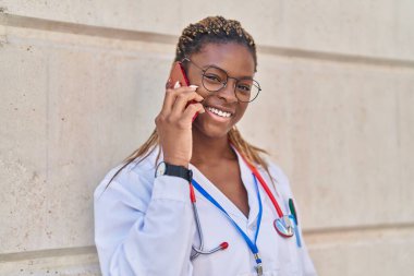 African american woman doctor smiling confident talking on smartphone at hospital