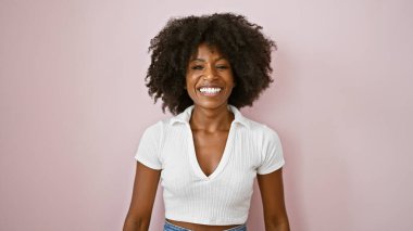 Afro-Amerikalı kadın pembe arka planda kendine güvenen gülümsüyor.