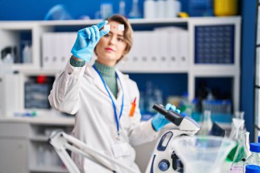 Young woman scientist using microscope looking sample at laboratory