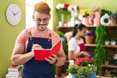 Çiçekçide dizüstü bilgisayar kullanan erkek ve kadın çiçekçiler.