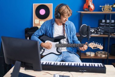 Young man artist singing song playing electrical guitar at music studio