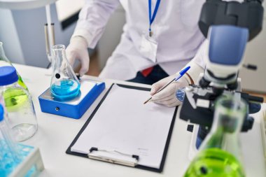 Genç İspanyol bilim adamı laboratuvarda sıvı yazım raporunu ölçüyor.