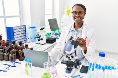 Laboratuvarda bilgisayar ve mikroskop kullanan Afrikalı Amerikalı kadın bilim adamı.