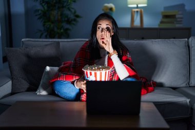 İspanyol kadın patlamış mısır yiyor kanepede eli ağızda film izliyor gizli dedikodular söylüyor, kötü niyetli konuşmalar fısıldıyor. 