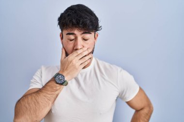 Beyaz arka planda duran İspanyol sakallı adam ağzıyla ağzını kapatmaktan sıkılmış. Huzursuz ve uykulu.. 