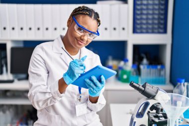African american woman scientist using touchpad at laboratory