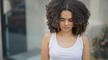 Genç, güzel, İspanyol bir kadın ciddi bir ifadeyle sokağa bakıyor.