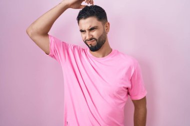 Pembe arka planda duran İspanyol genç adamın kafası karışmış ve soru sormayı merak ediyor. Şüpheyle kararsız, kafa kafaya düşünerek. Düşünceli kavram. 