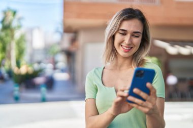 Sokakta akıllı telefon kullanan kendine güvenen genç bir kadın.