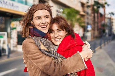İki kadın anne ve kızı sokakta birbirlerine sarılıyorlar.
