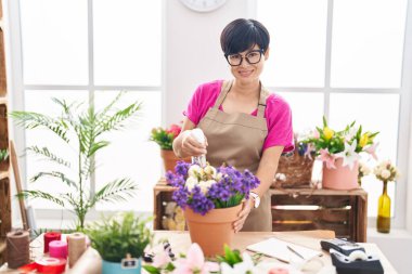 Middle age chinese woman florist using diffuser working at flower shop