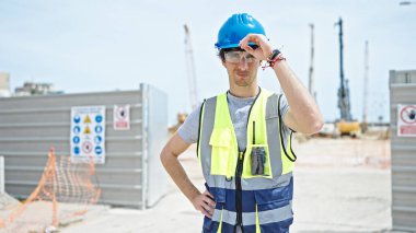 İspanyol asıllı genç bir mimar inşaat alanında ciddi bir yüzle duruyor.