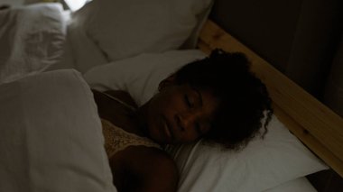 Afro-Amerikalı kadın yatakta uzanıyor. Yatak odasında uyuyor.