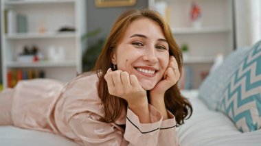 Young woman smiling confident lying on bed at bedroom