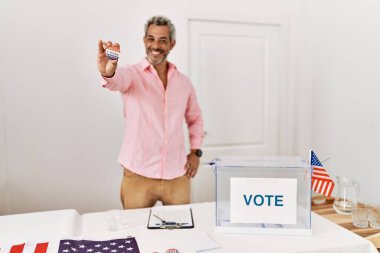 Middle age grey-haired man electoral table president holding vote badge at electoral college