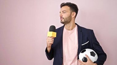 Genç İspanyol futbolcu muhabir, izole edilmiş pembe arka planda röportaj yapıyor.